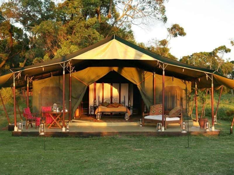 Canvas safari tent lit warmly on a lodge lawn